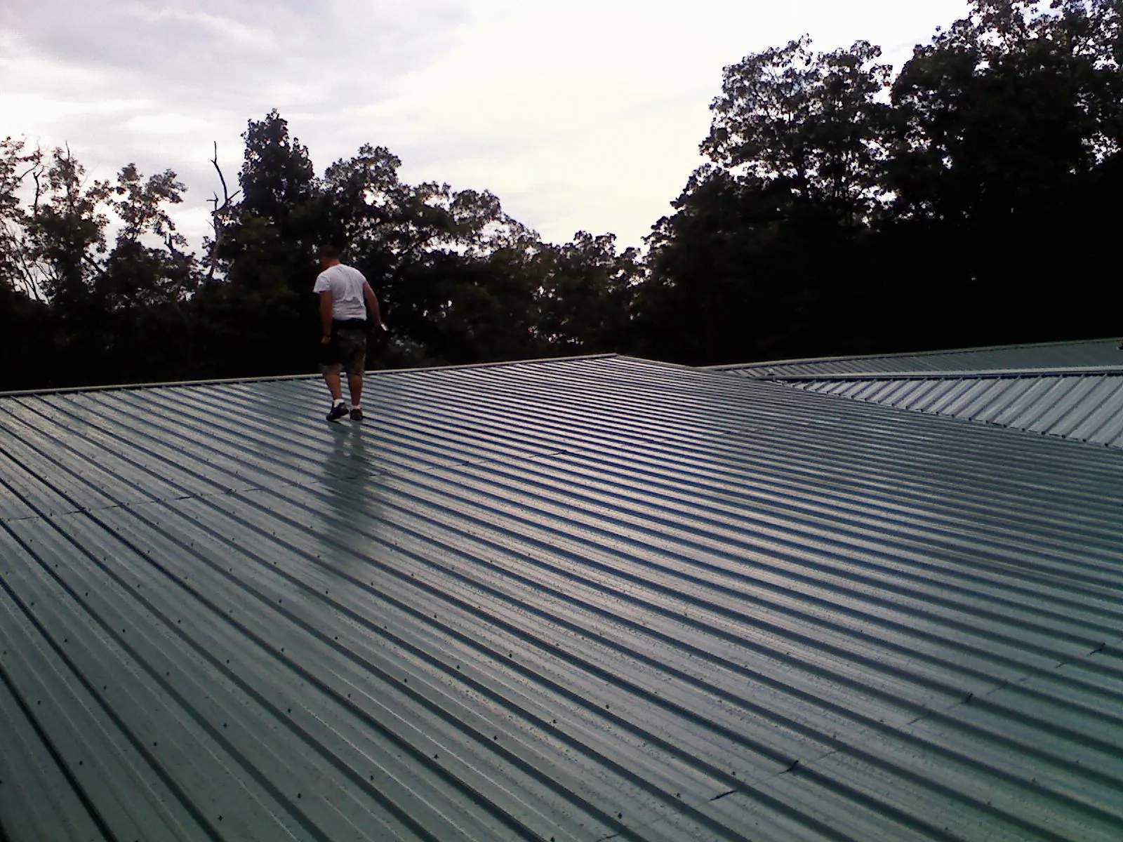 Roofer walking a wide expanse of new green metal roofing in Park City