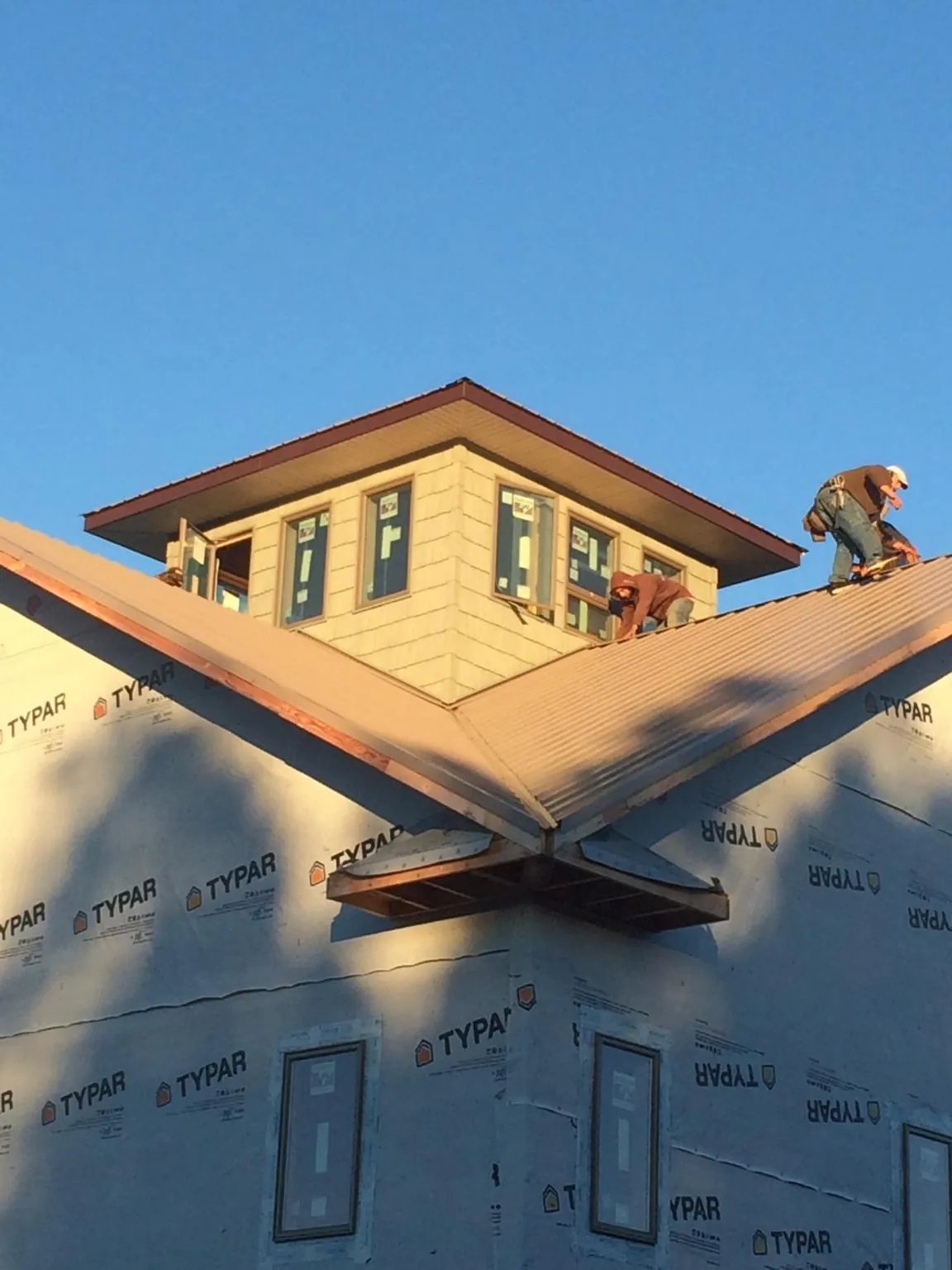 Roofers working around a rooftop cupola on a new metal roof at sunset — Roof Waterproofing in Park City by Roofing Brothers